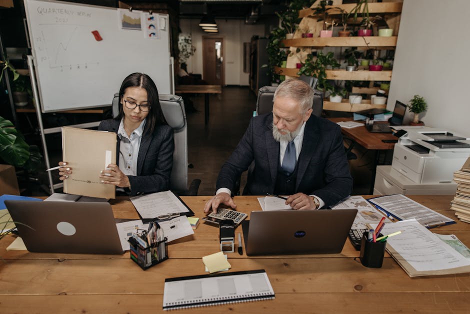 Business professionals in a modern office working collaboratively at desks with laptops.
